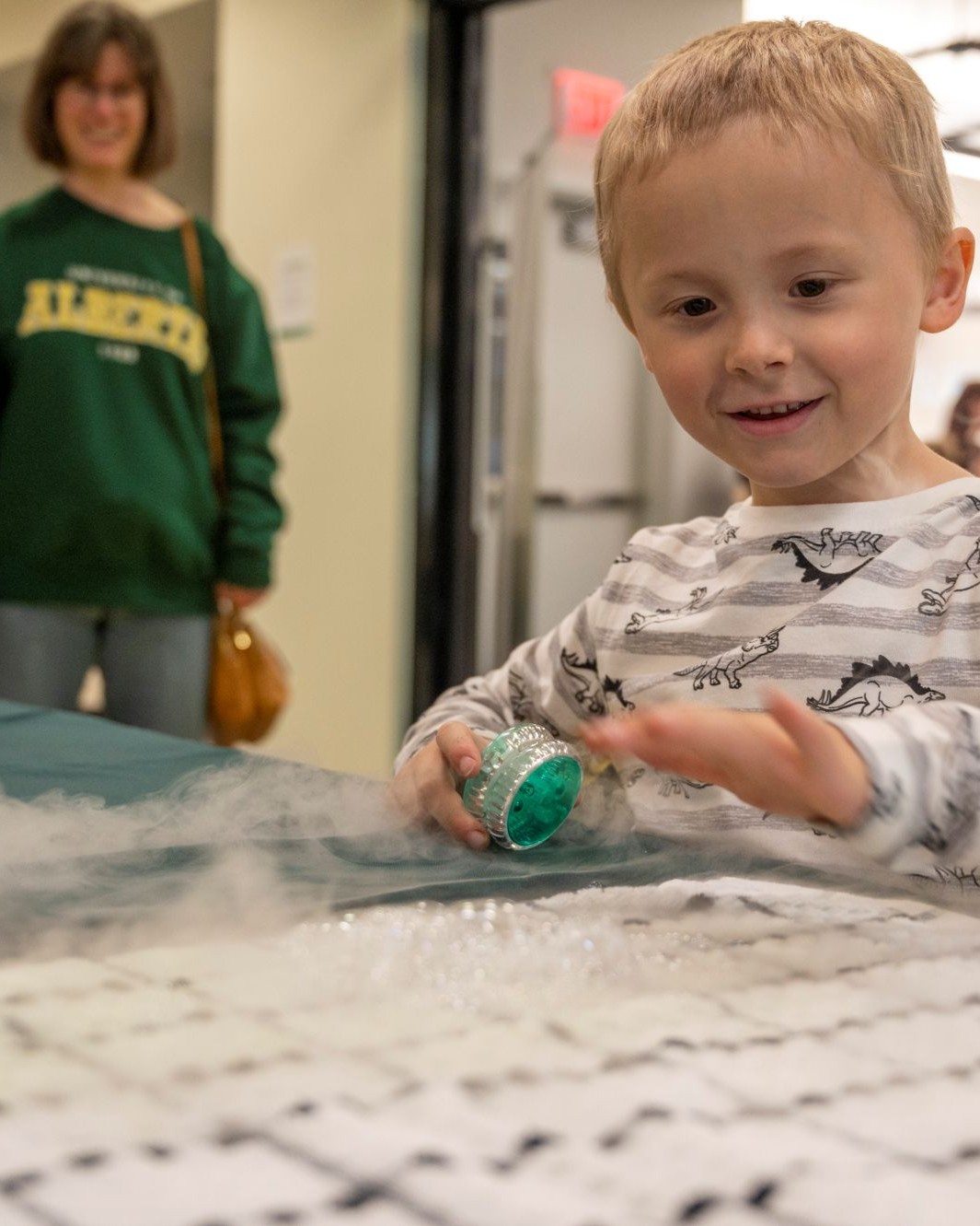 Young boy playing a game with an adult standing in the background