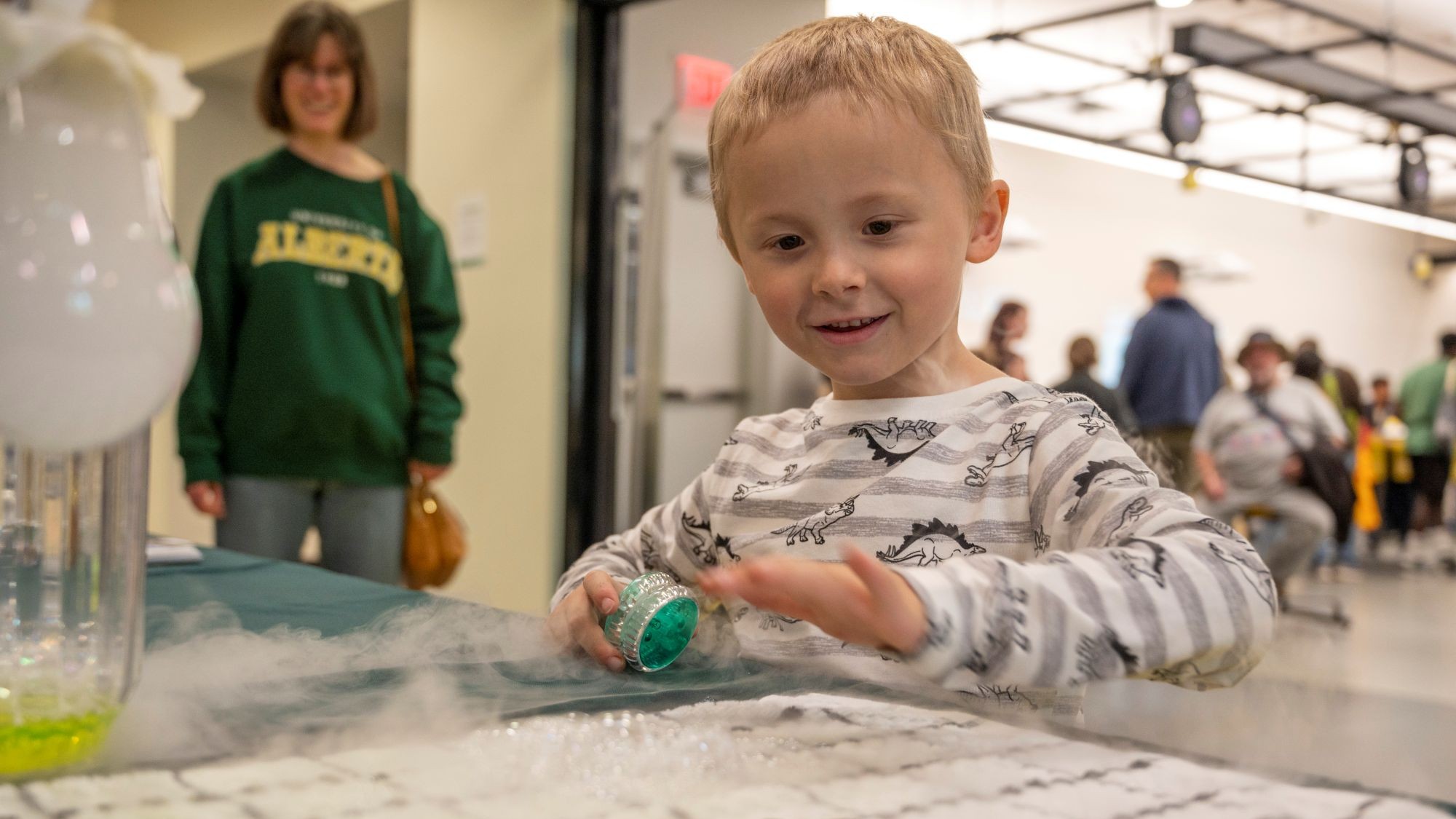 Young boy playing a game with an adult standing in the background