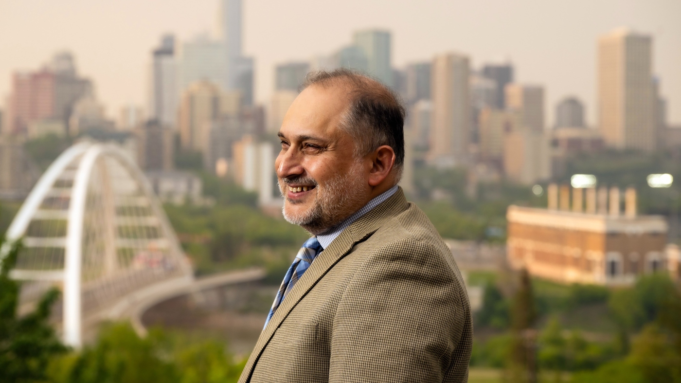 Headshot of Dr. Murtaza Haider with downtown Edmonton and the River Valley behind him.