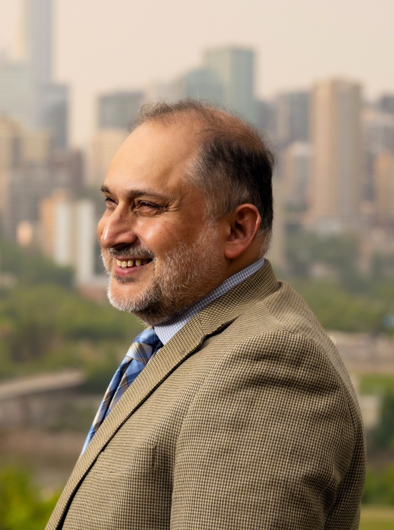 Headshot of Dr. Murtaza Haider with downtown Edmonton and the River Valley behind him.