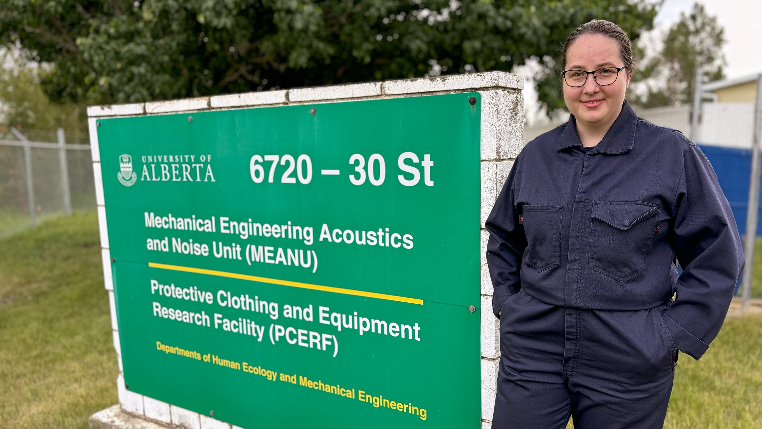 Elena Kosareva standing next to the Protective Clothing and Equipment Research Facility building sign