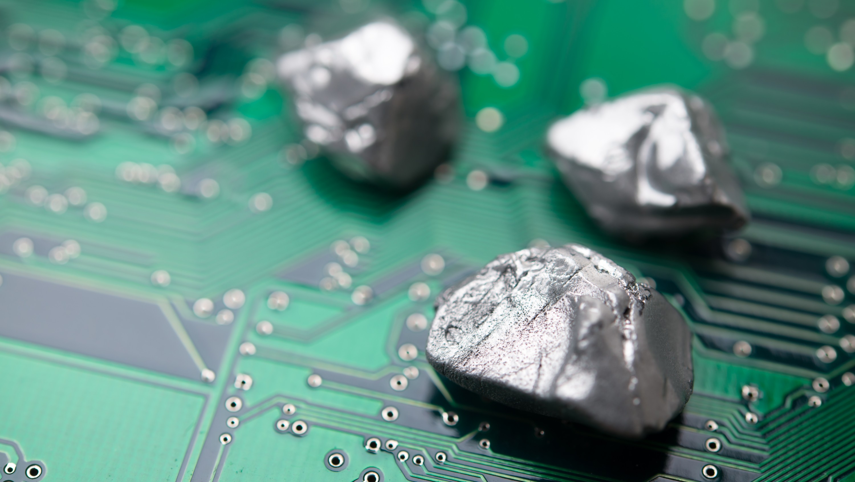 Three silvery, raw metallic nuggets rest on the surface of a green printed circuit board. (Photo: Getty Images)