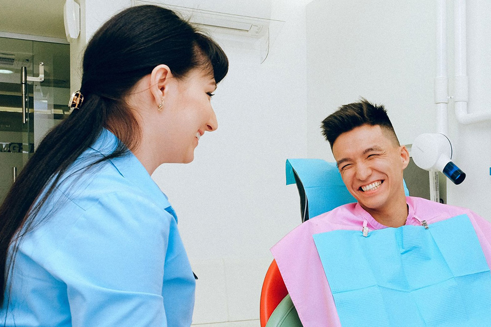 Dental assistant smiles at patient in chair.