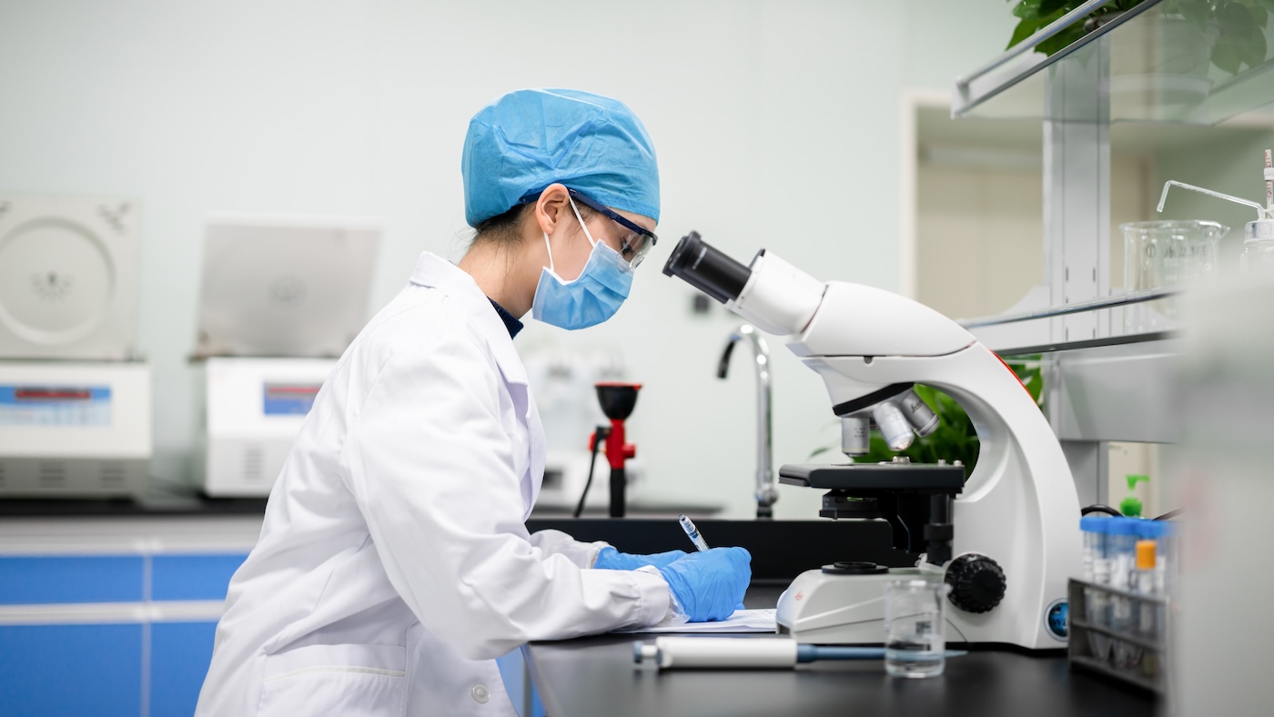 Researcher making notes next to a microscope