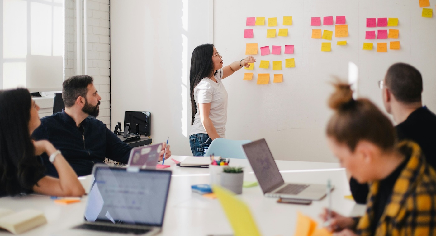 Group of people brainstorming around a table using sticky notes on the wall