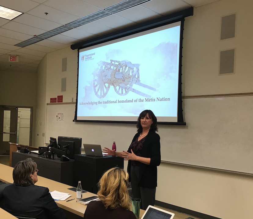 Yvonne Poitras Pratt presents in front of an Metis identity image