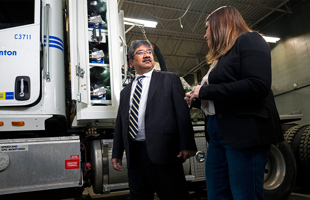 Indoor photo of Rebecca Goldsack showing a hydrogen-fuelled truck to Amit Kumar