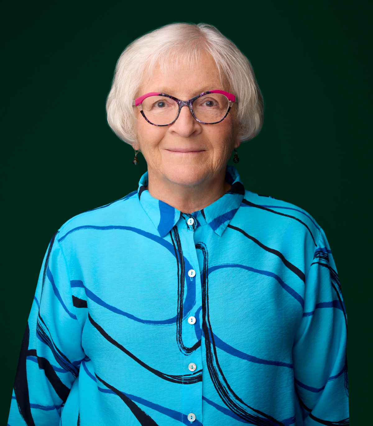 Judy Mill stands in front of a green backdrop.