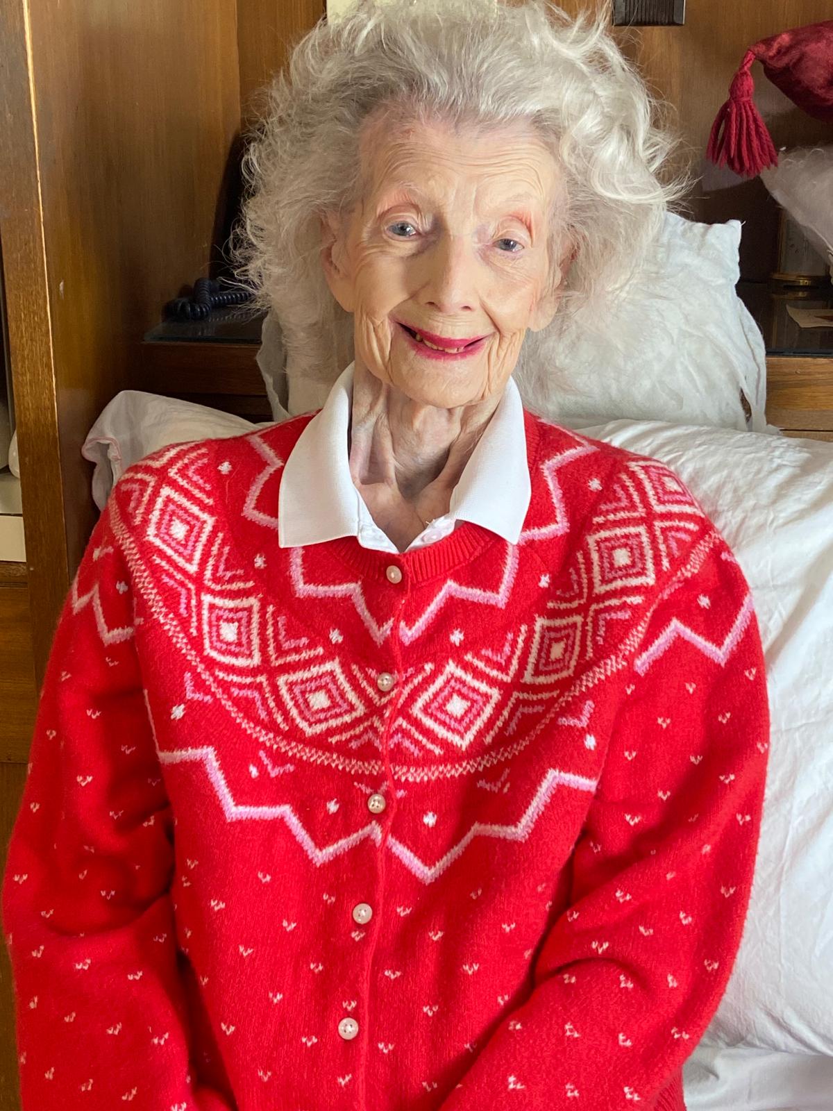 Mary McEachern at 102 years old, wearing a red sweater. 