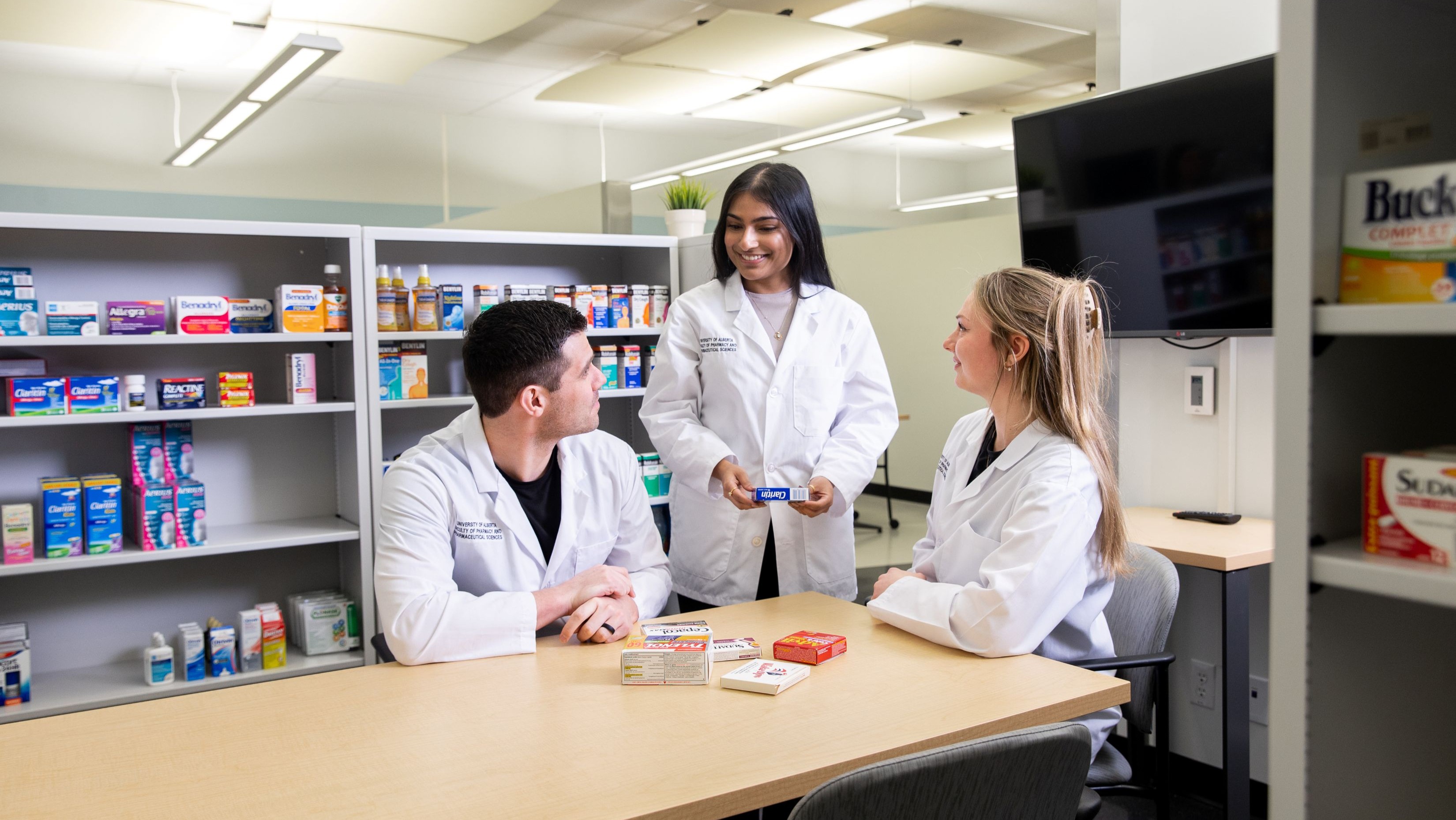 Three pharmacists smiling around a table