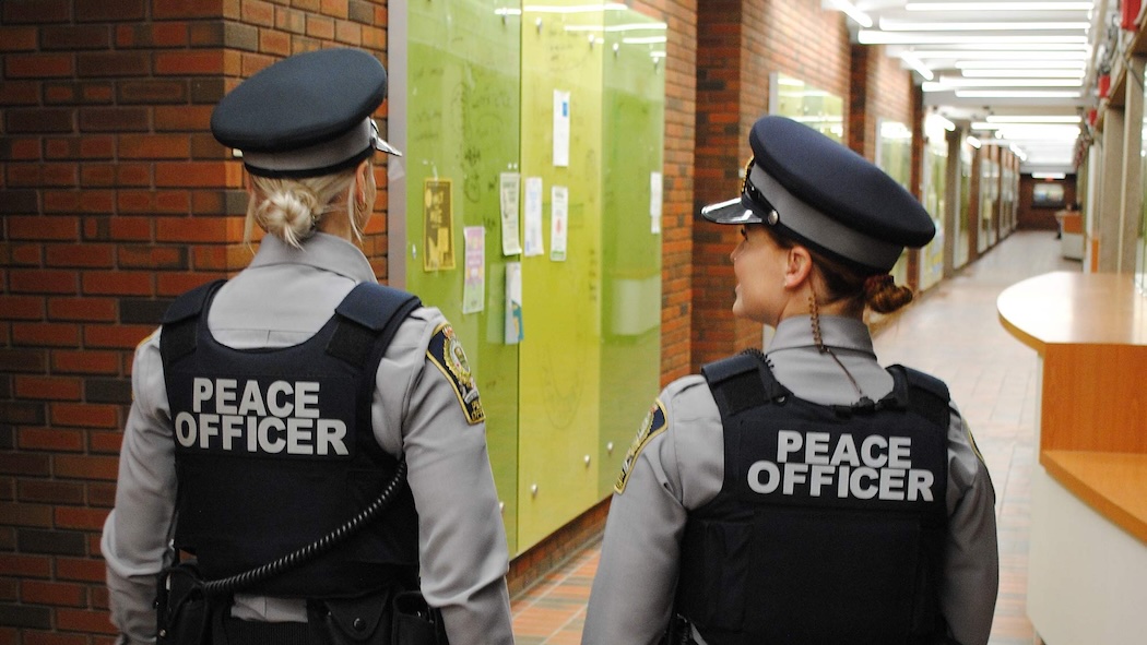 The backs of two peace officers inside a building on North Campus