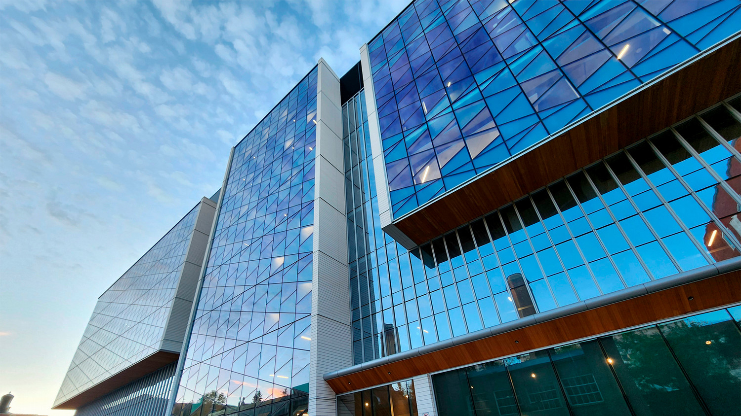 The University Commons building in the morning, blue sky reflected in its many windows.