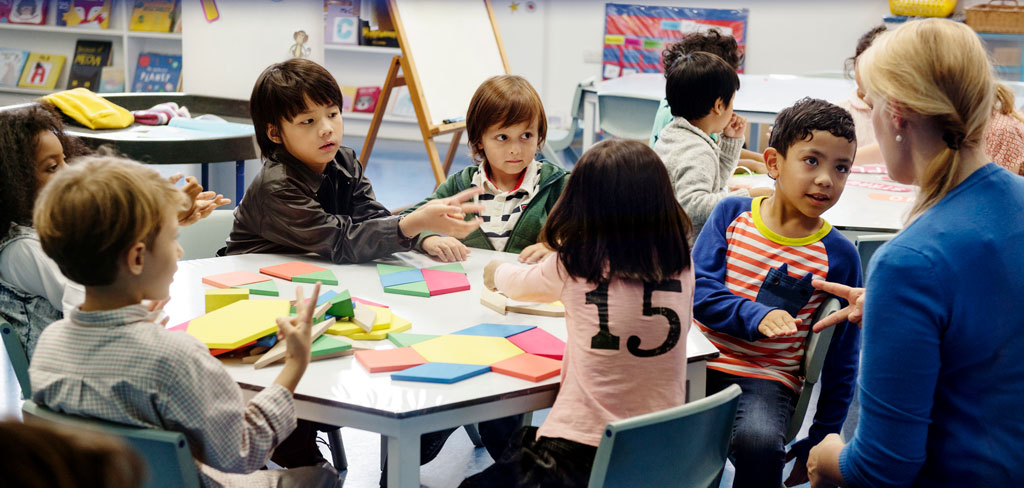 Teacher in a classroom of young children sitting at a table