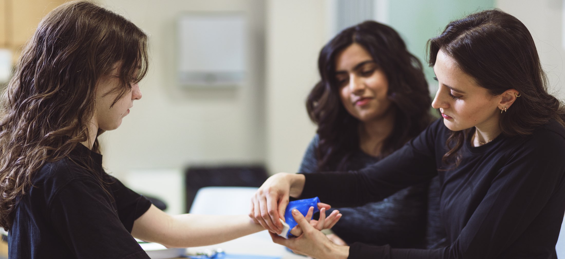 Physiotherapist and physiotherapy student taping up a patient's wrist
