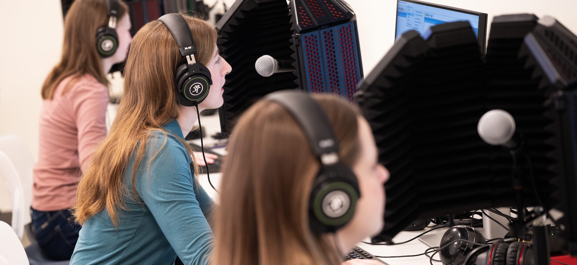 Three patients do speech tests wearing headphones in front of computers and speaekers