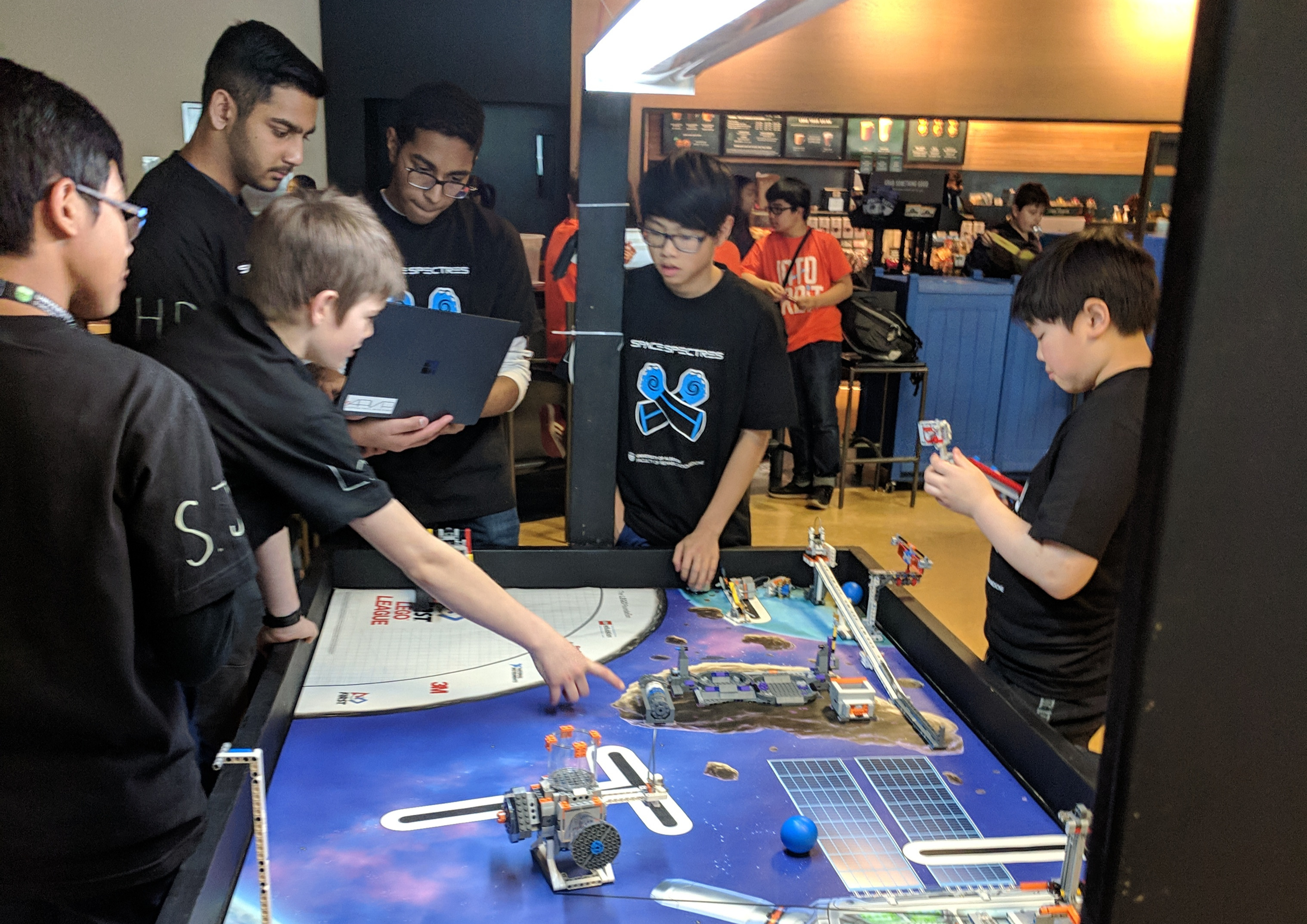 Students surrounding a table with robotics in action