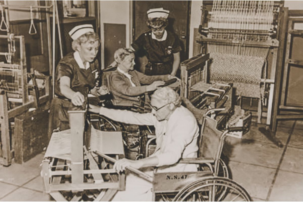 An occupational therapist helps a person using a wheelchair, in black and white