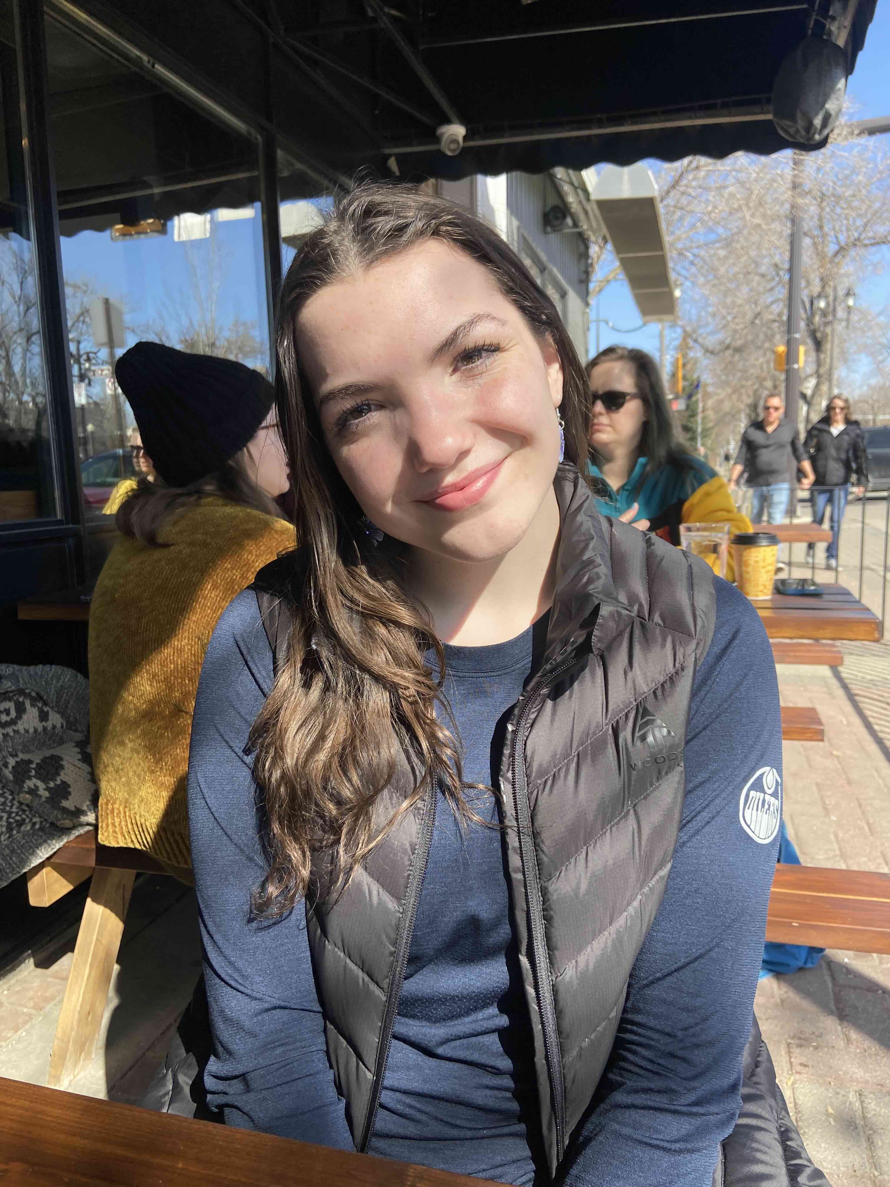 Katie Hart smiling while sitting at a table on a patio.