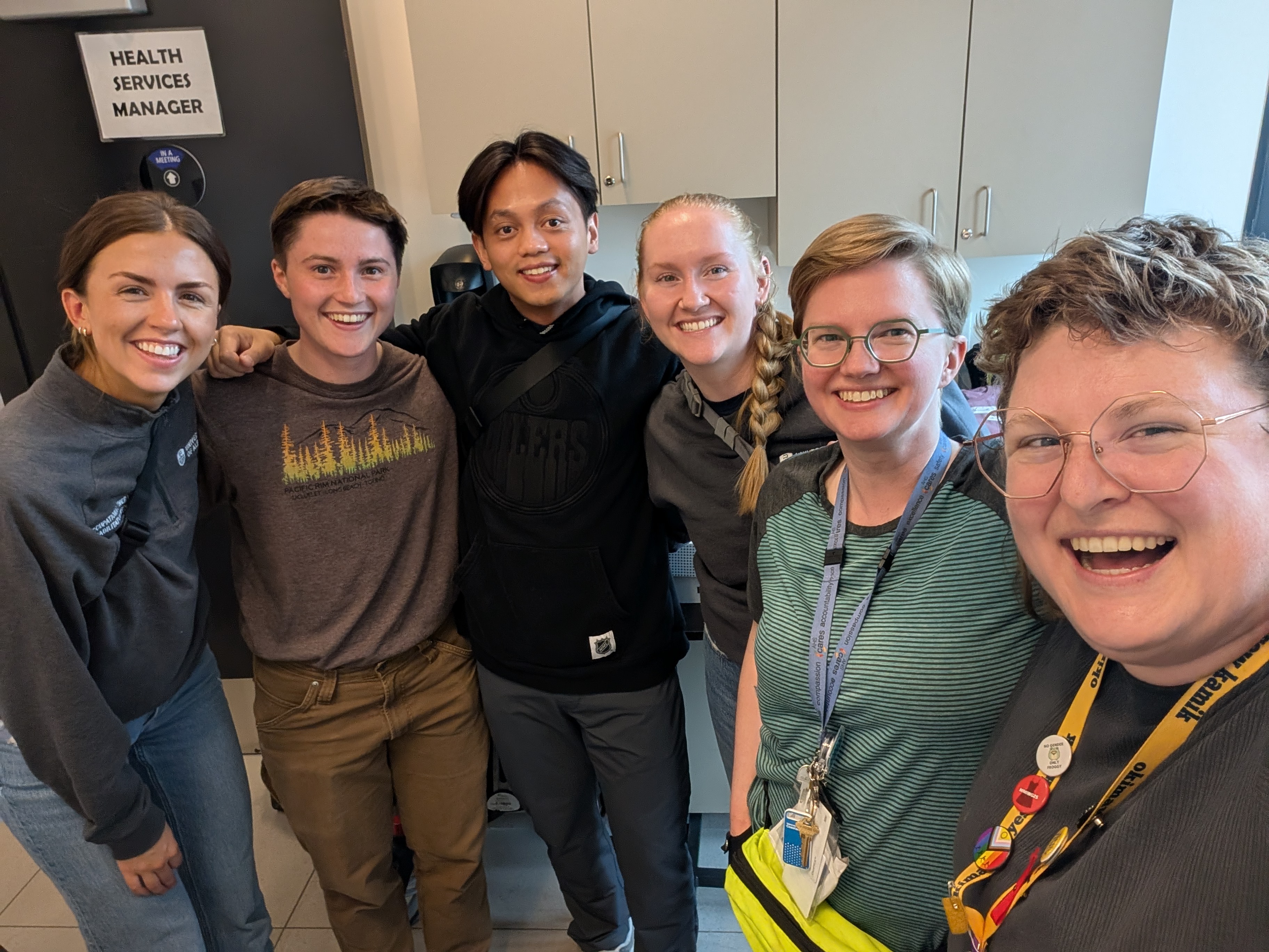 Six smiling OT students and instructors gathered together at the walker clinic.