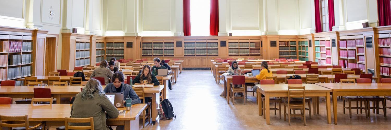 students sitting at tables, studying in library