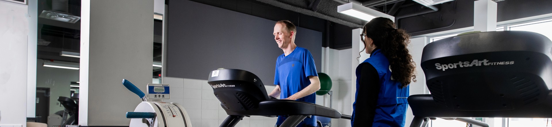 Man on a treadmill with a fitness trainer