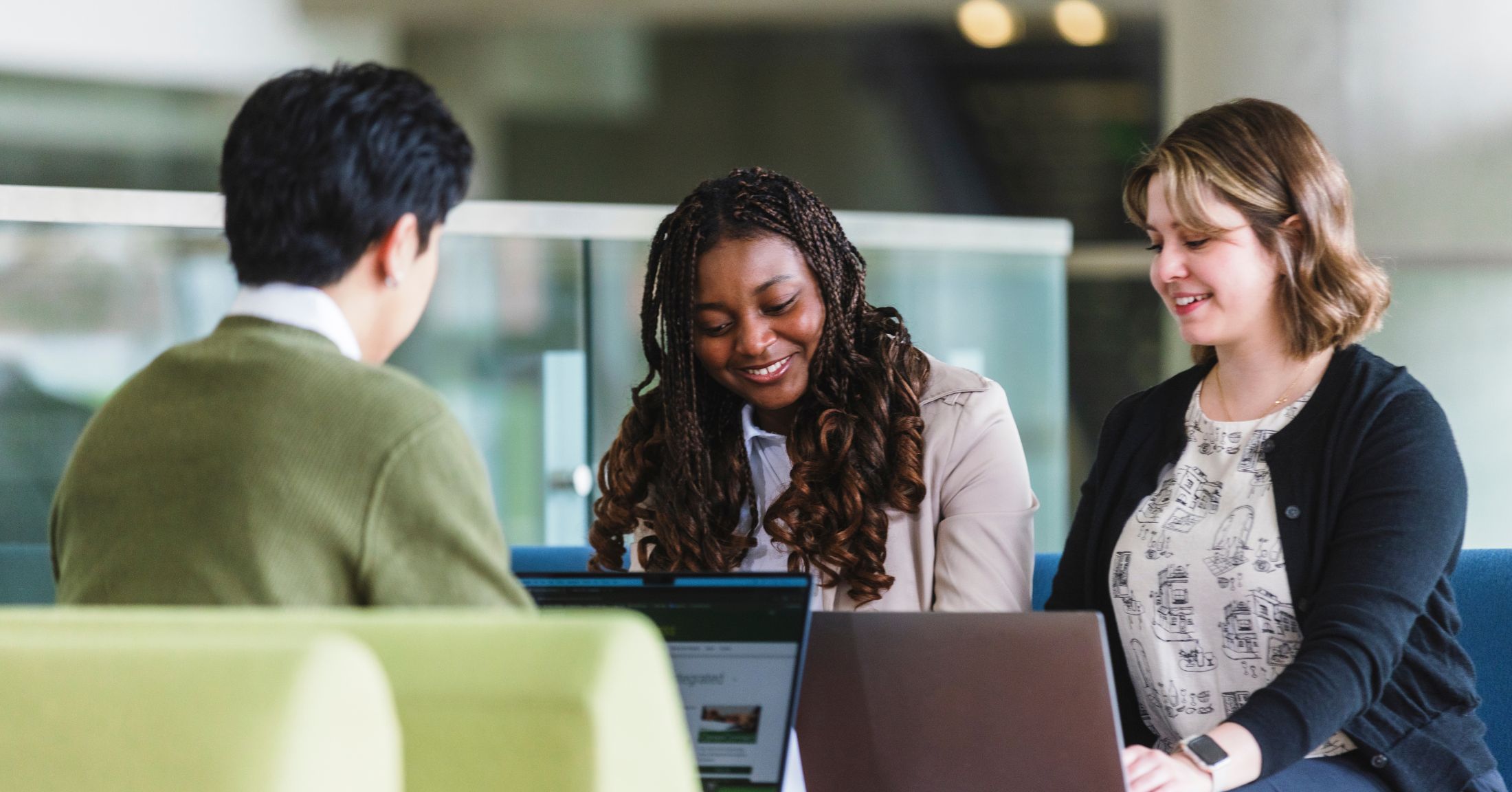 three students are working on a project together, sitting at a table in a bright room
