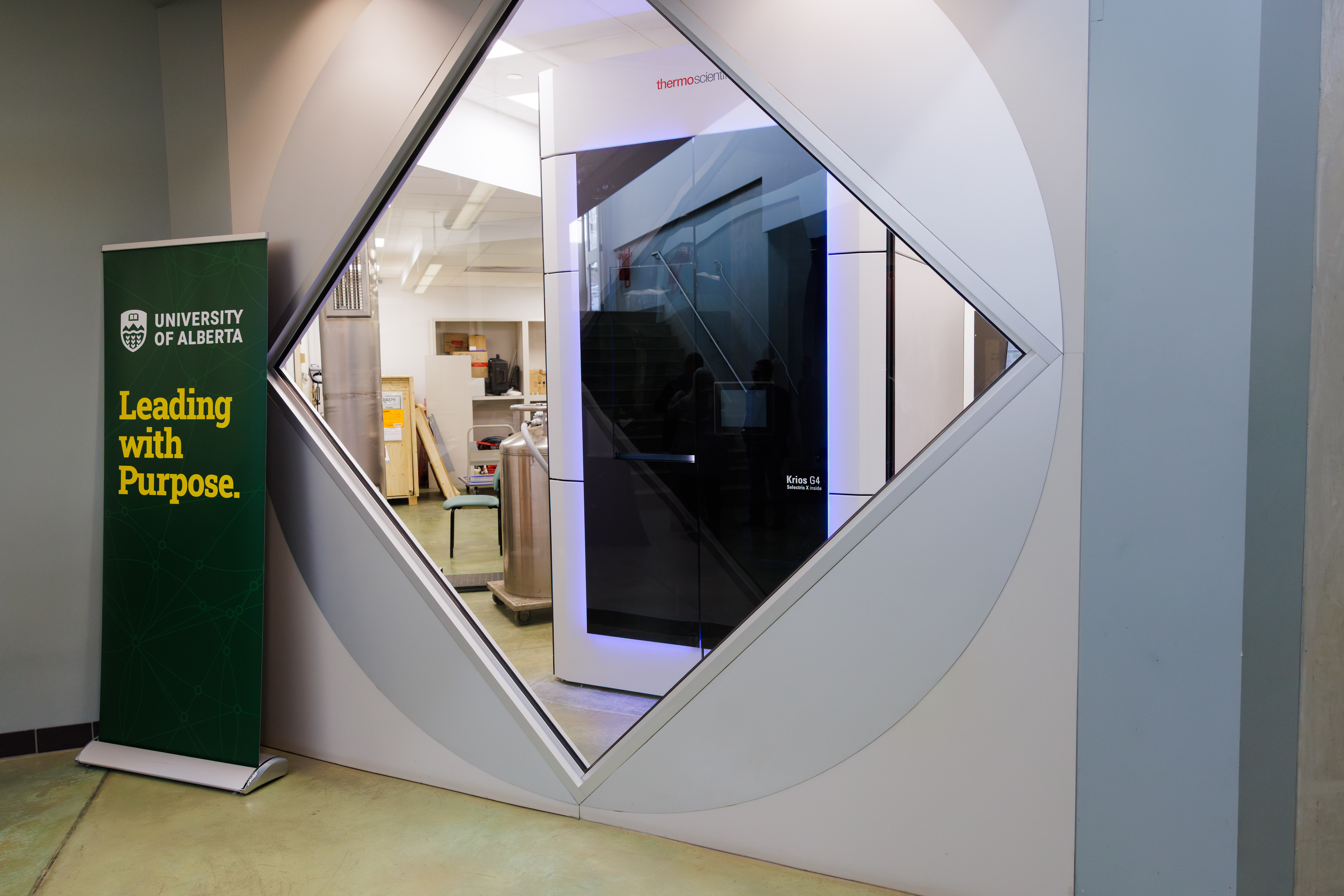 A banner that reads leading with purpose and has the university of alberta logo in front of cryogenic electron microscope