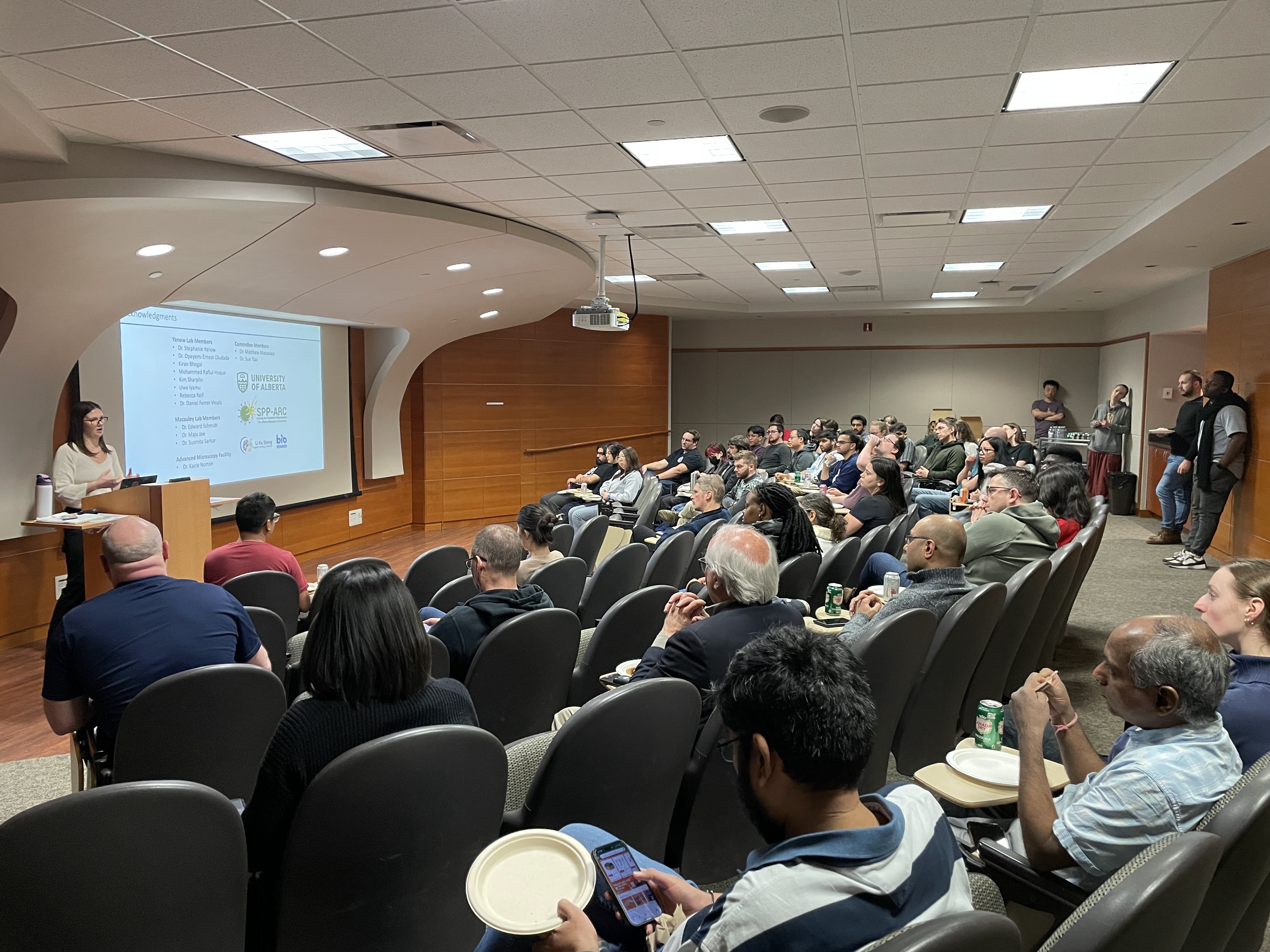 A crowd of faculty and trainees listen to a presenter. 