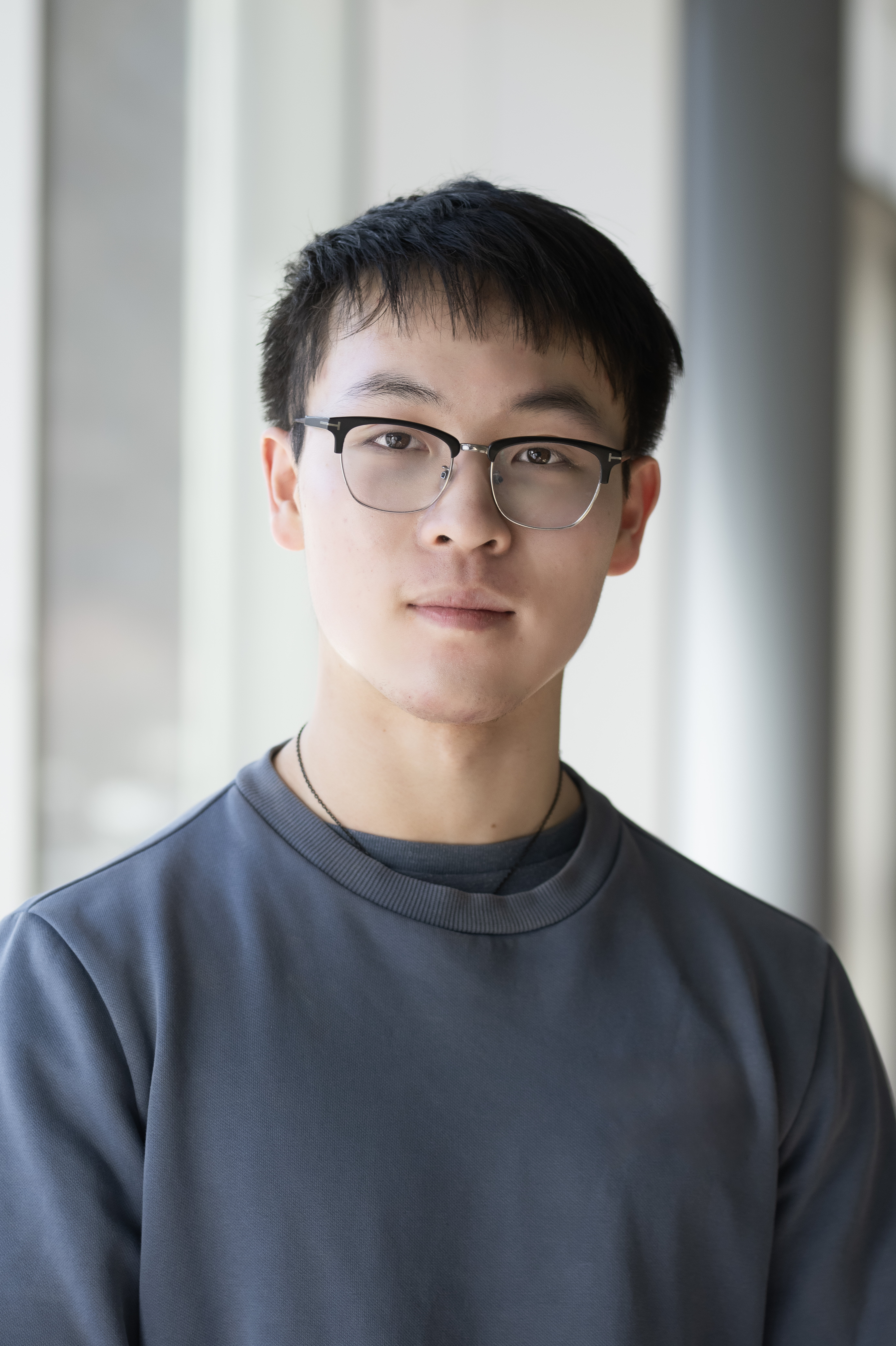 A young asian male in a sweatshirt and glasses