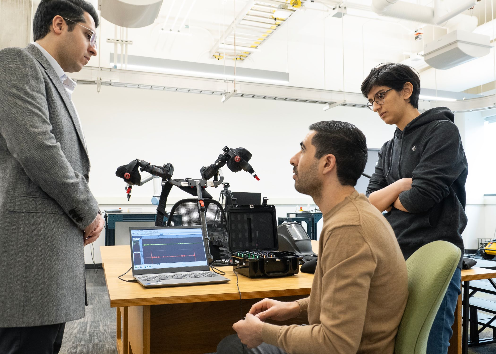 CIC executive director Ali Golabchi and graduate teaching assistants Niromand Jasimi and Negar Riahi analyze exoskeleton motion and signal data during biomechanical research.
