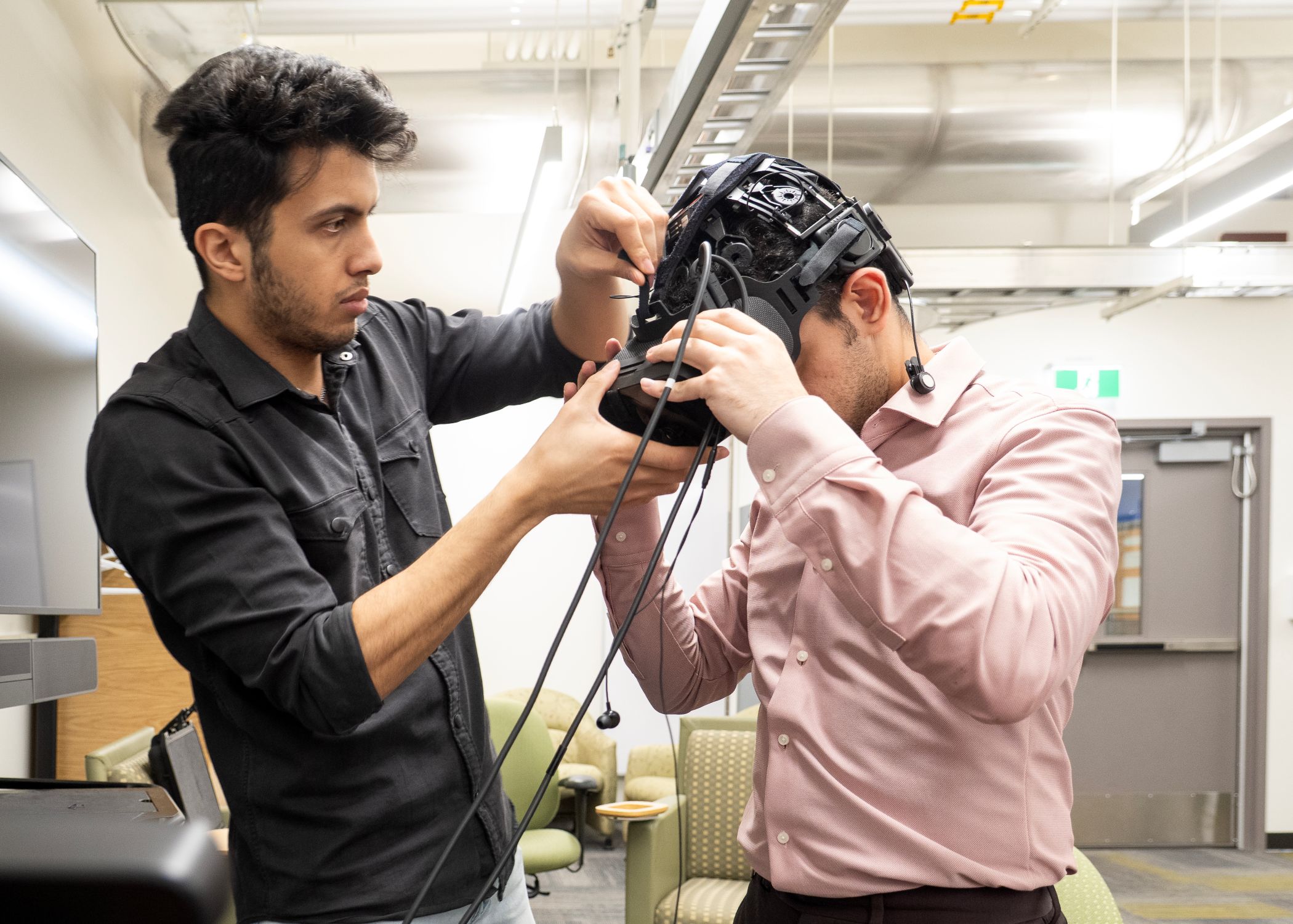 Graduate teaching assistant Eren Shahrokhishahraki and PhD researcher Mohammad Rezaeiashtian set up an electroencephalogram (EEG) headset during a neurotechnology experiment.