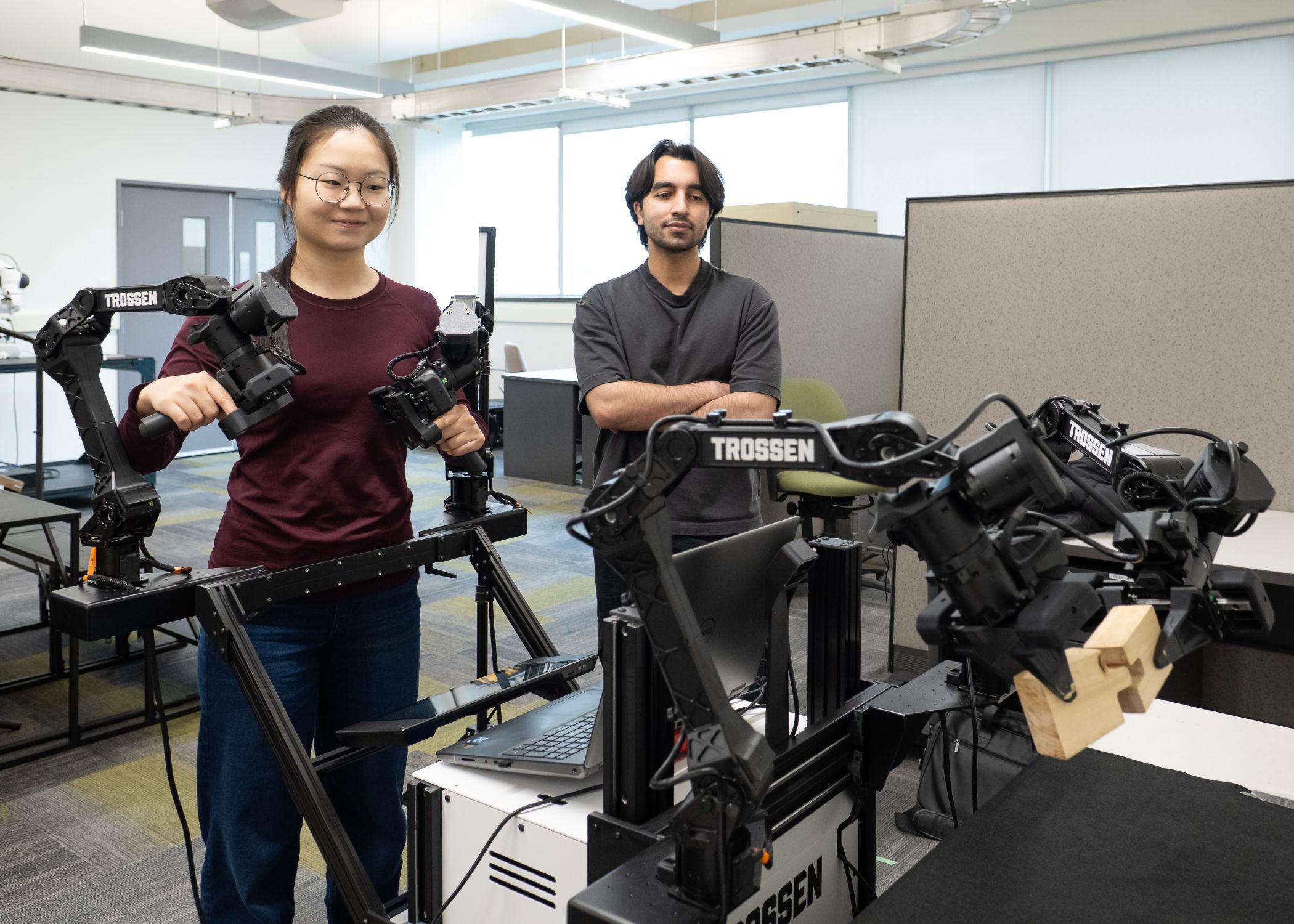 Graduate teaching assistant Yuezhen Gao and graduate research assistant fellow Muhammad Talha demonstrating and controlling a dual-arm robotic manipulation system during a teleoperation robotics experiment.
