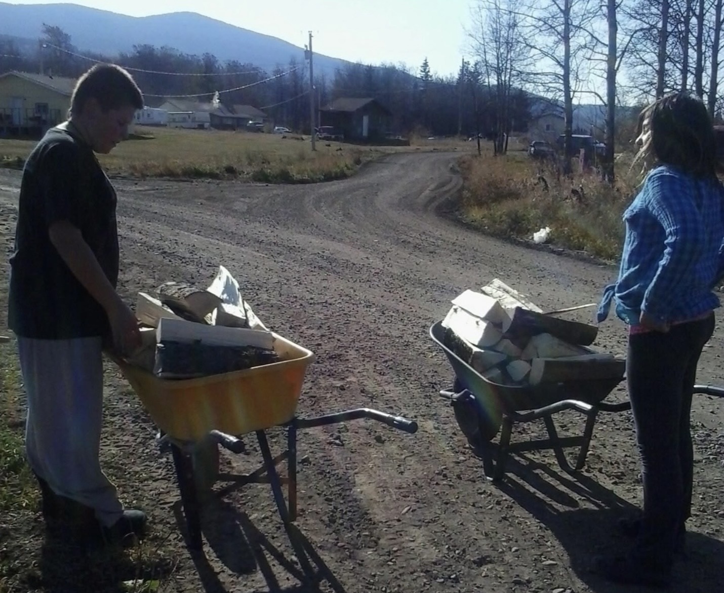 Marc (left) and his sister Devina (right) hauling wood in their home community of Susa Creek.