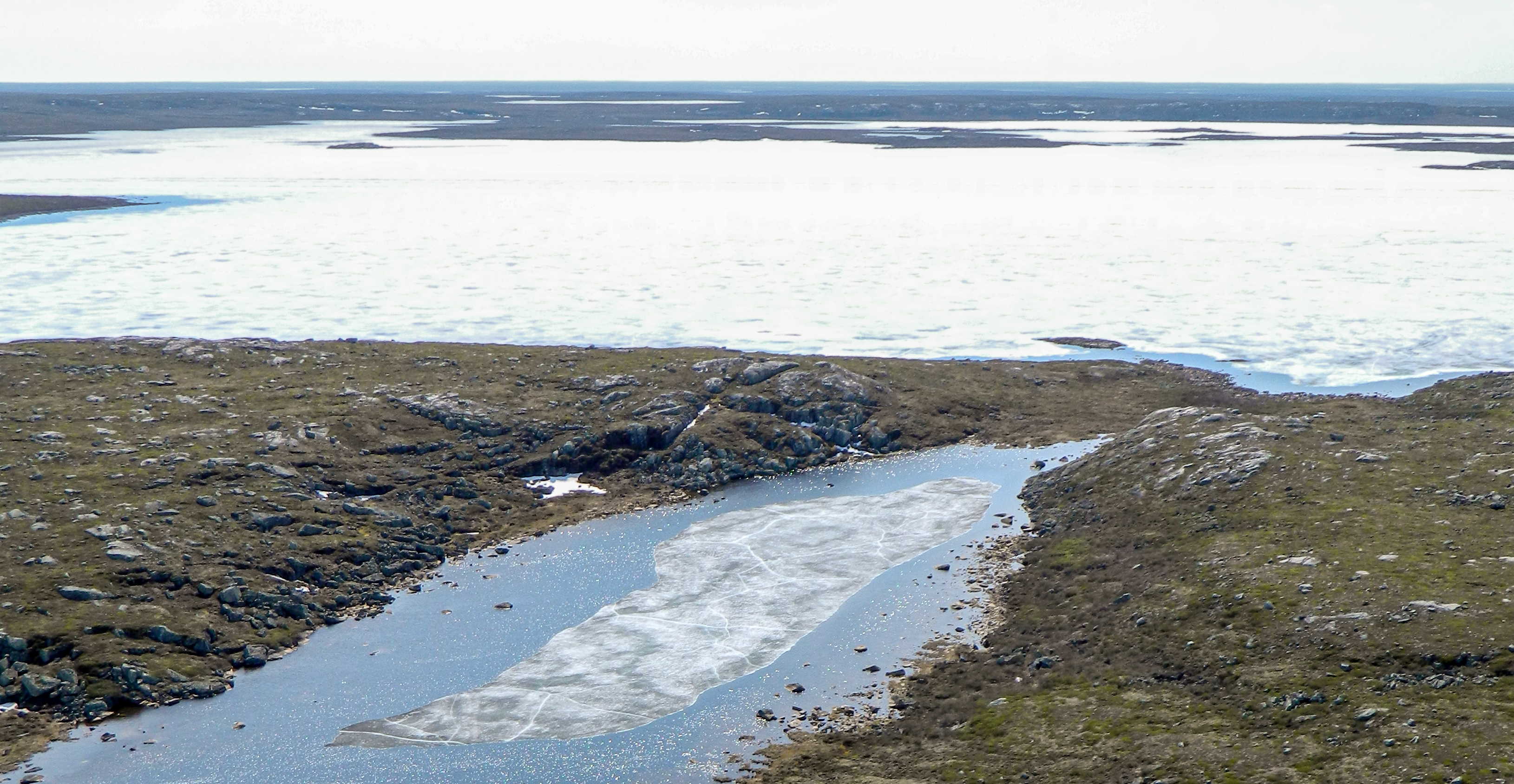 Ice floating in a river approaching a frozen lake in NWT