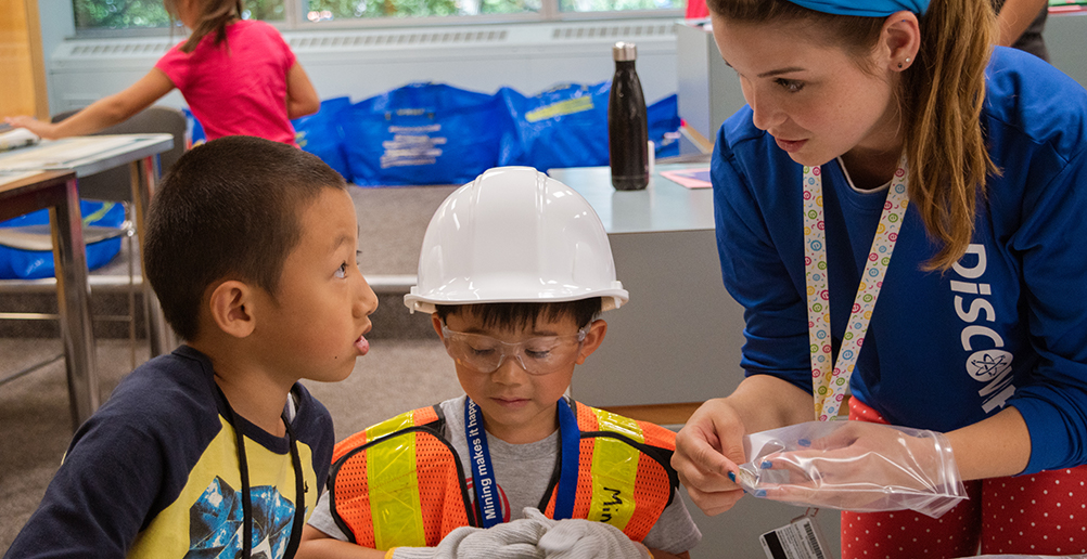 A DiscoverE instructor helping two campers with a mining activity.