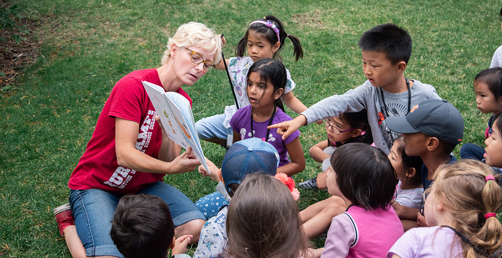 A DiscoverE volunteers reads a book to a group of young campers.