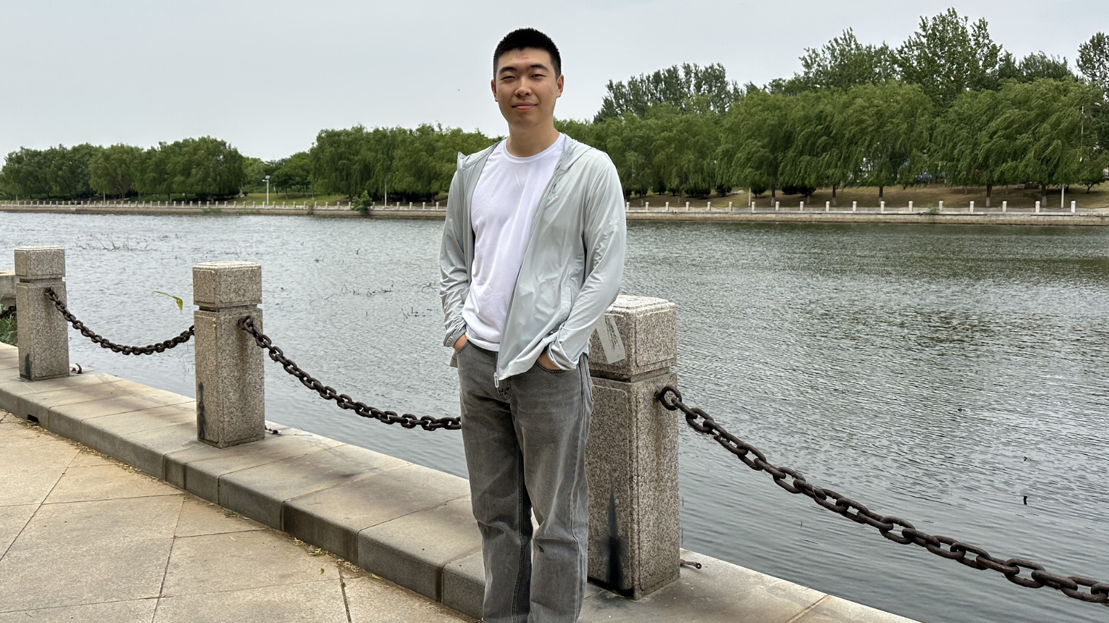 YouQian standing in front of a lake with trees.