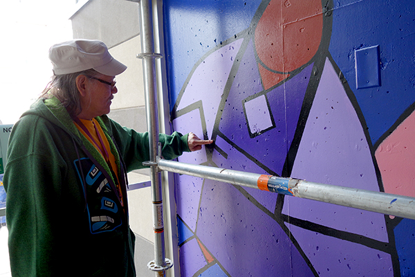 Mural artist Jerry Whitehead traces the letters "W" and "E" in his mural.