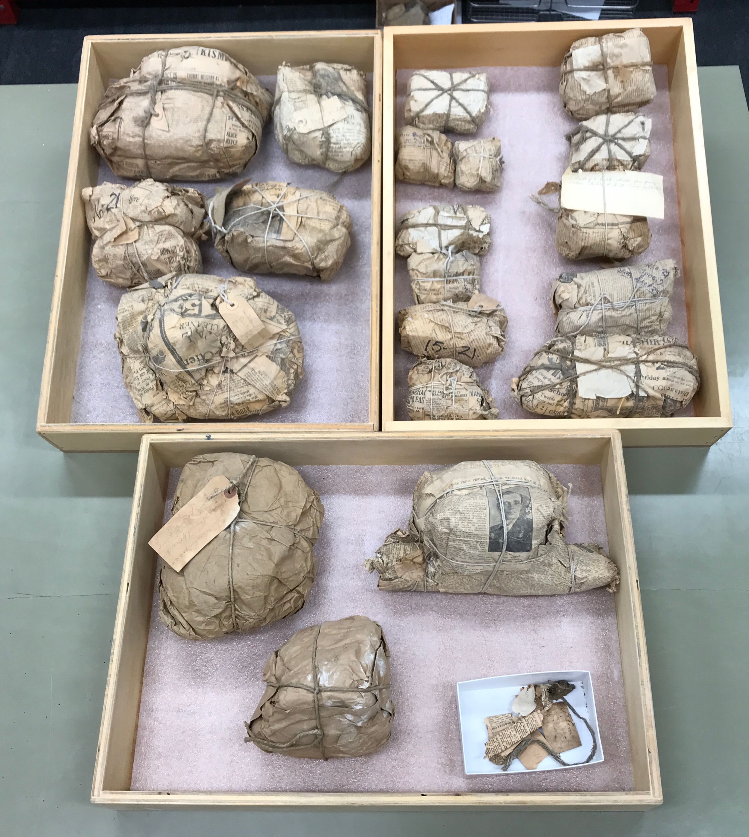 Three wooden boxes containing dinosaur bones wrapped in old newspaper (Photo courtesy Clive Coy)