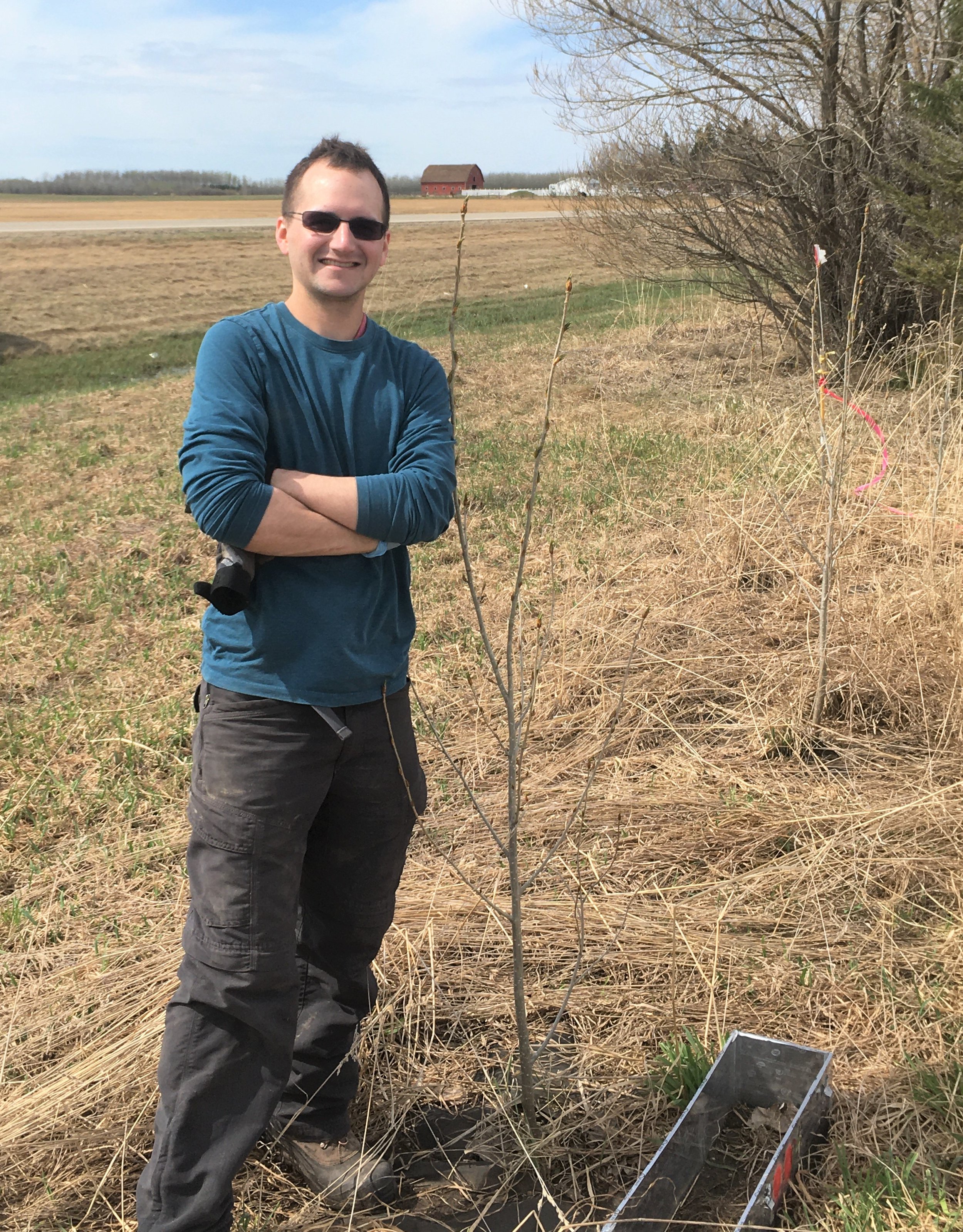 Researcher Cole Gross stands next to a newly planted sapling near an agricultural field. (Photo: Supplied)