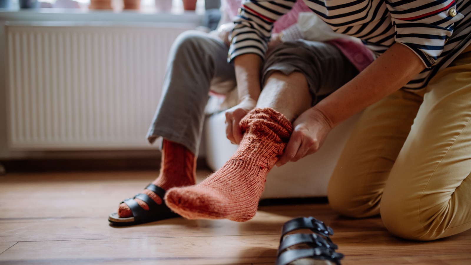 Caregiver helps man put on socks. (Photo: Getty Images)