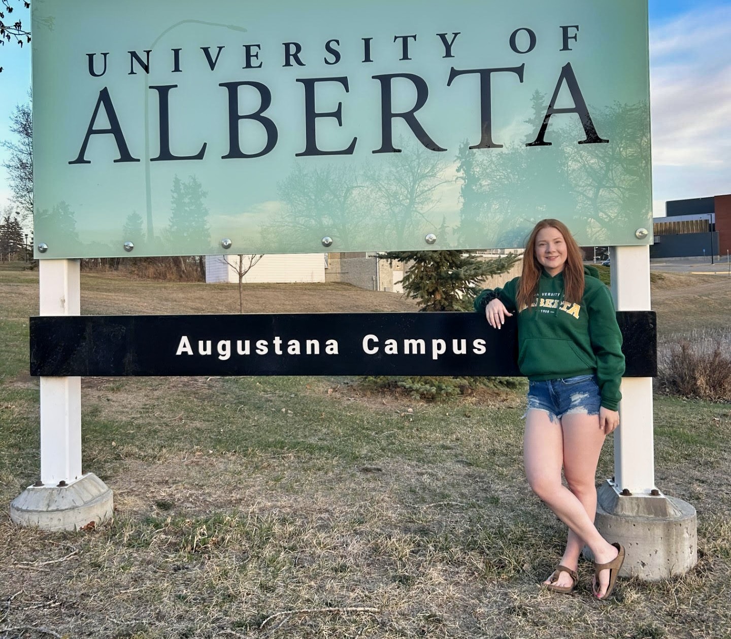 Carly Rombs stands in front of an Augustana Campus sign at the University of Alberta's campus in Camrose.