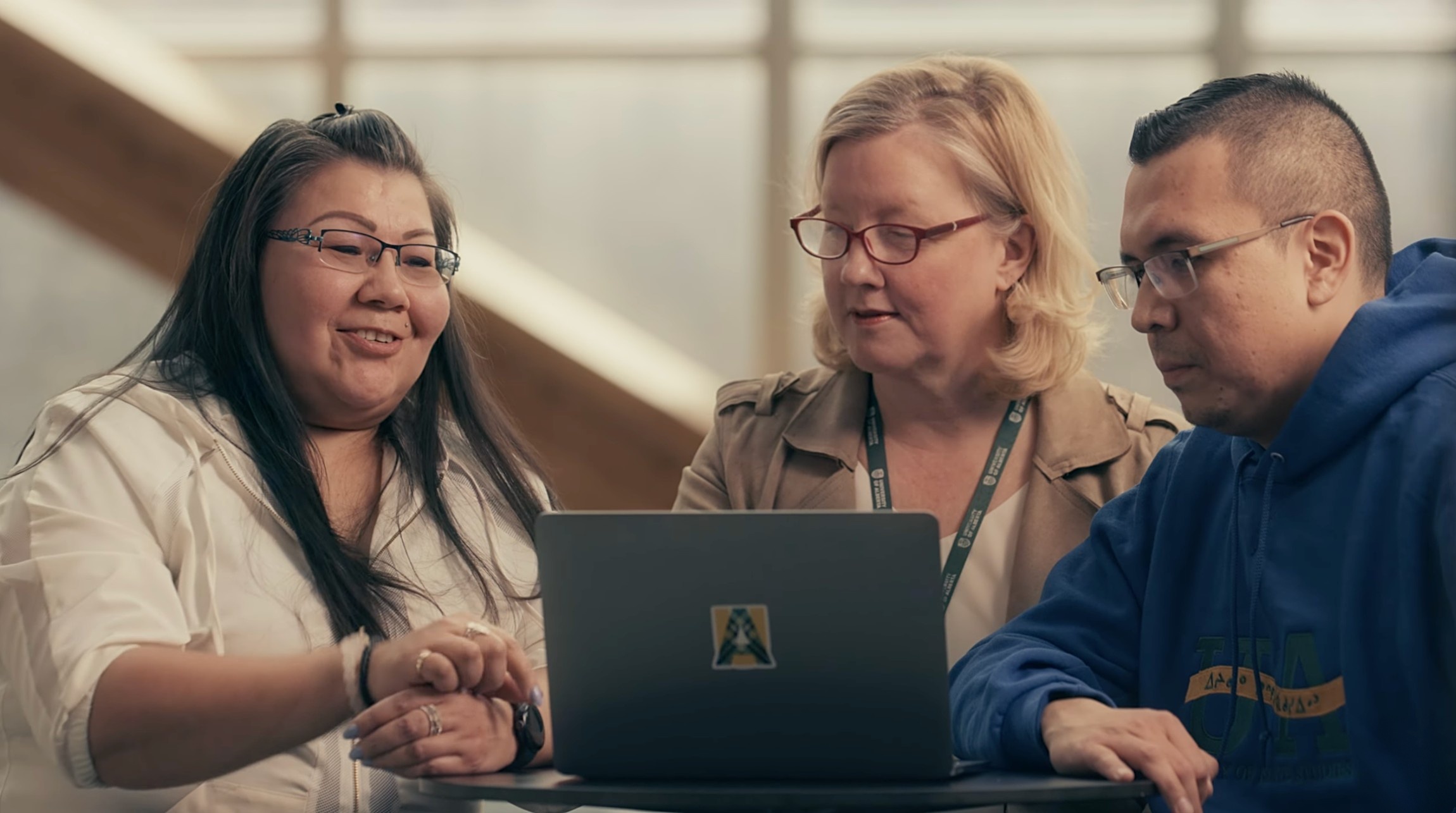 Three members of the U of A community engage in a discussion while looking at a laptop. (Photo: Supplied)