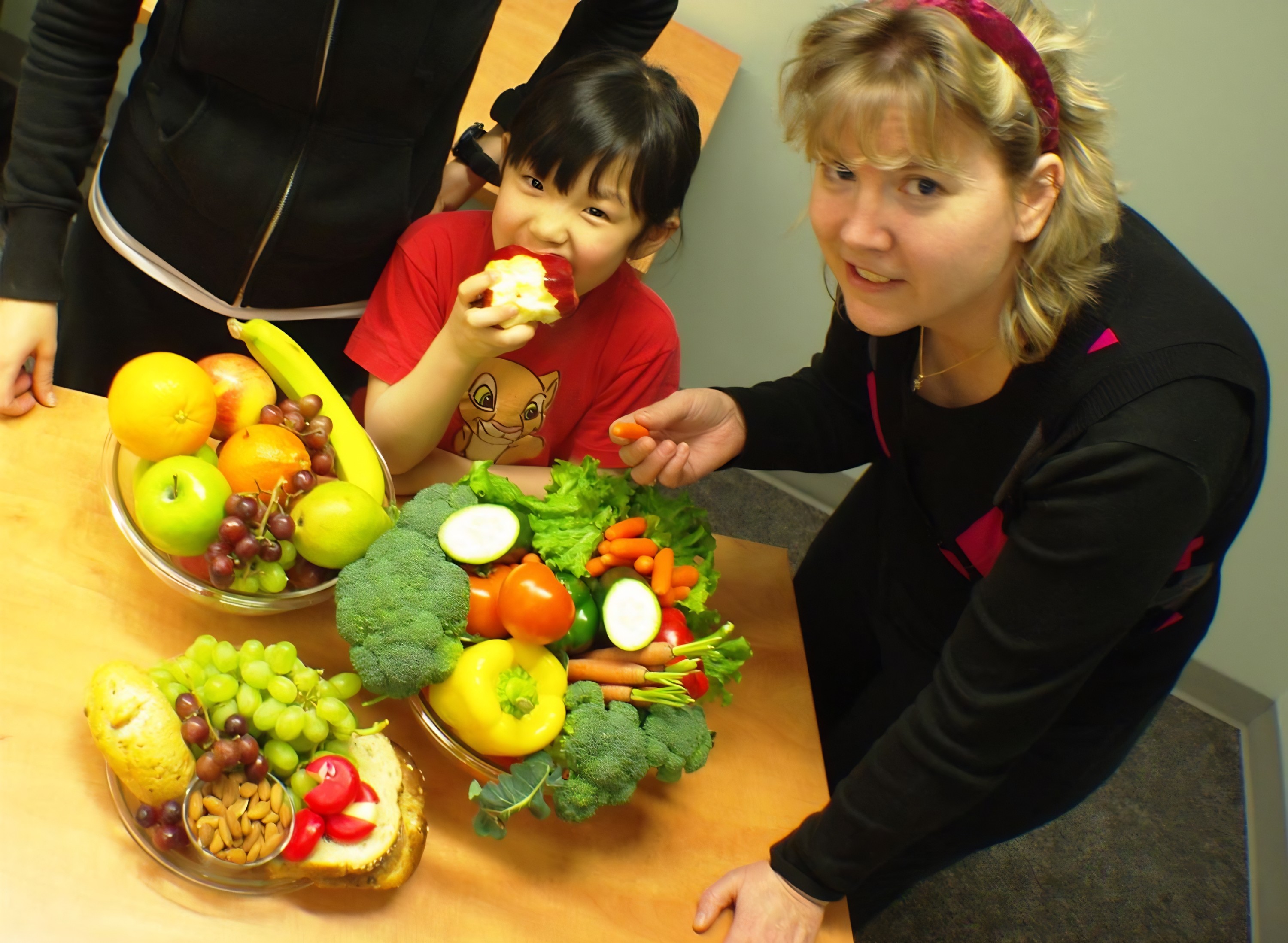 Nutrition researcher Diana Mager is pictured with her child at a table full of healthy foods like fruit and vegetables.