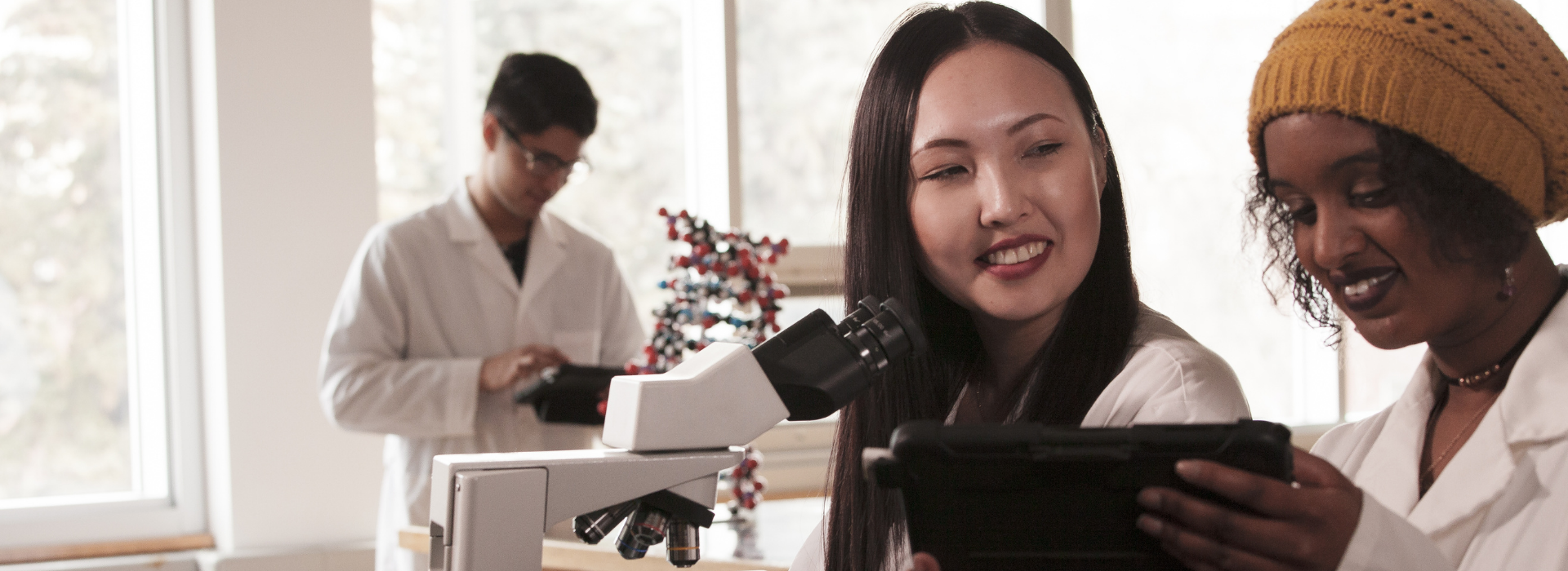 Two students in a CSJ laboratory in front of a microscope