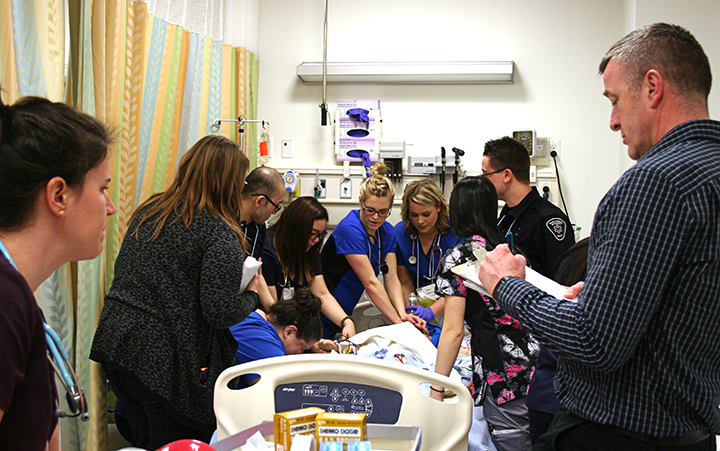 Facilitator observes students partcipating in an ER simulation
