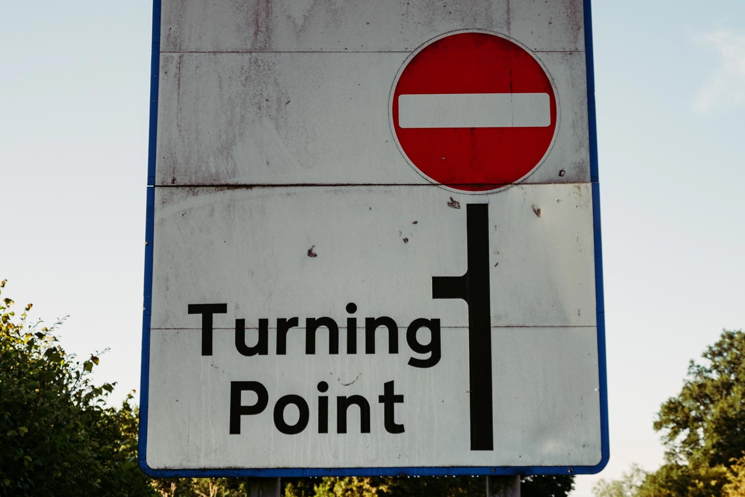 Road sign with a no-passing symbol at the end of the road, with the words, Turning Point, and a line leading to the left