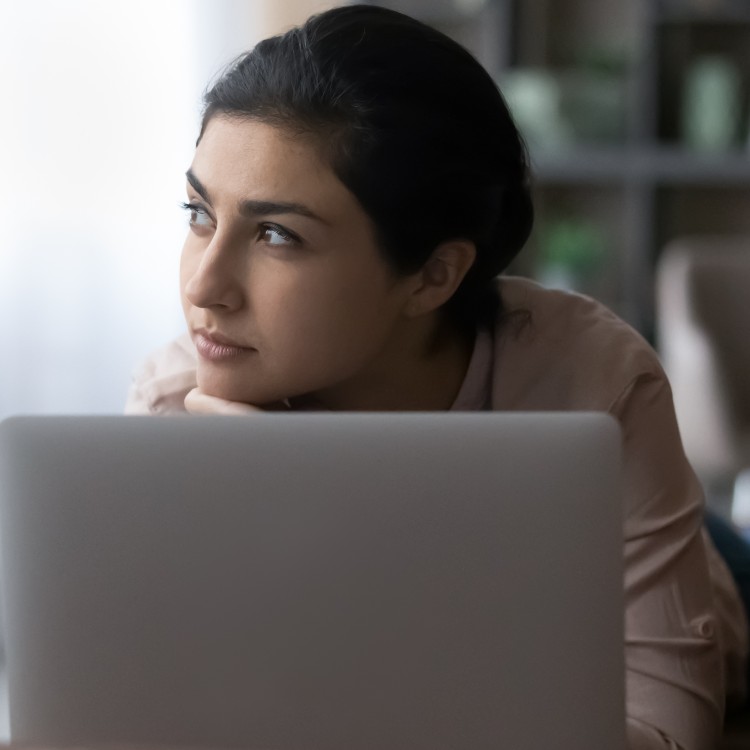 Woman staring of into the distance with laptop in front of her