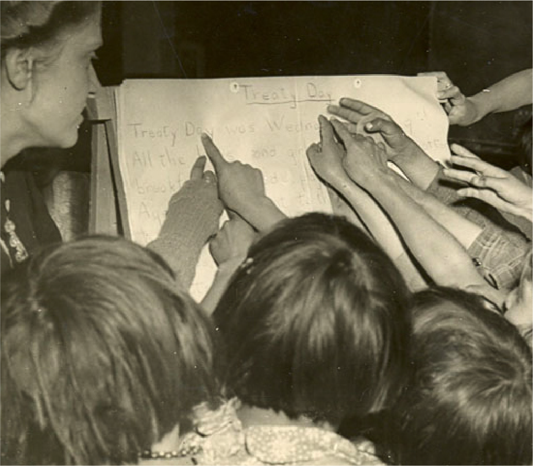 Children pointing to a lesson on the past Treaty Day with staff, Morley Residential School, AB, 1945