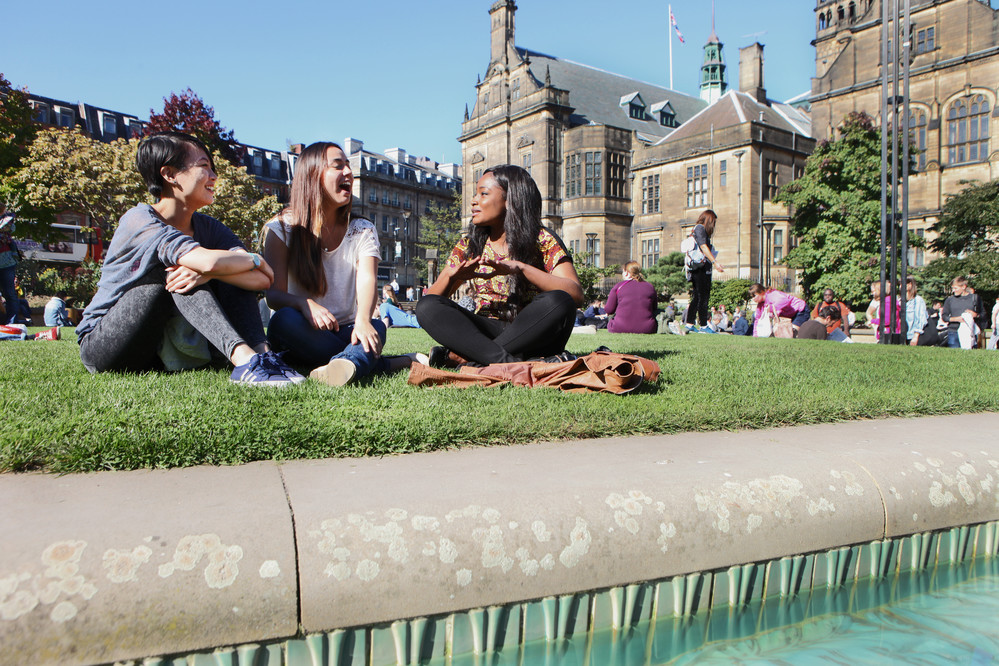 sheffield uni with students sitting on the grass chatting and laughing